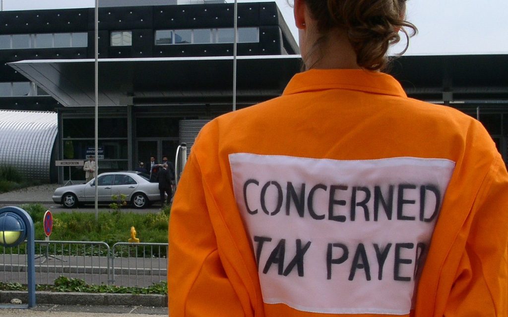A person in a workers overall seen from behind with the words "concerned tax payer" printed on the back.
