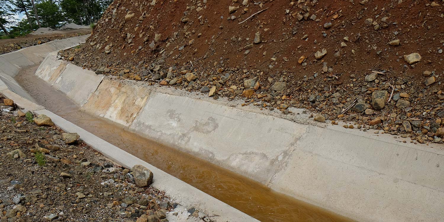 Водный канал из бетона, проложенный вдоль склона бугра.