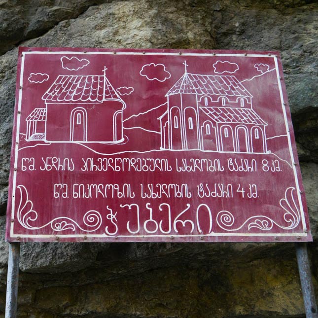 A hand-made sign with Georgian writing, indicating sight-seeing destinations.