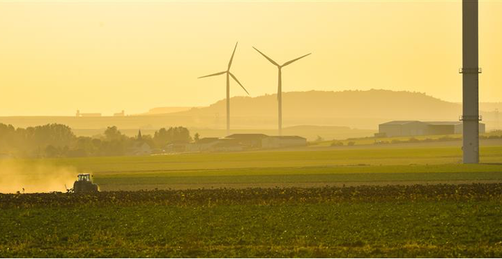 Wind turbines and a yellow sky, agricultural fields and ploughing